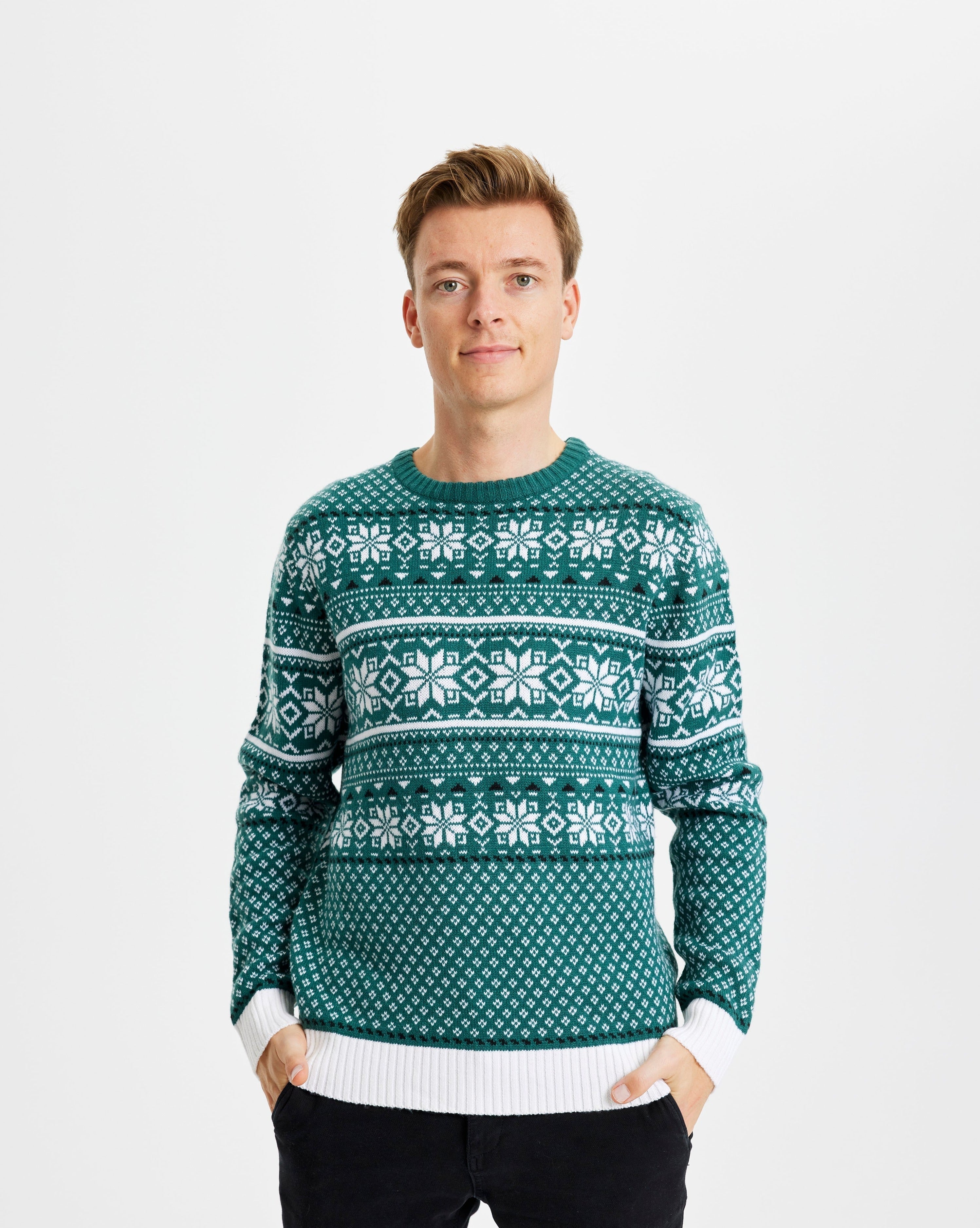 Un homme souriant portant un pull vert de Noël avec des flocons de neige.